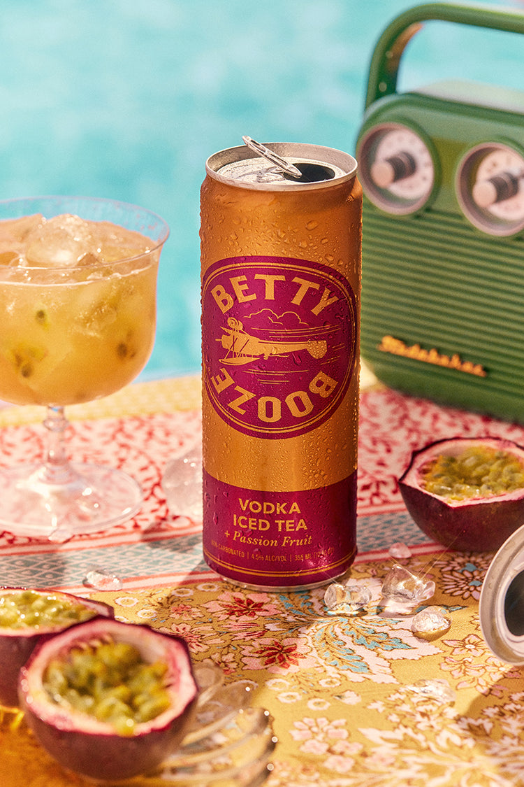 Betty Booze Vodka Iced Team + Passion Fruit Can next to a stereo, passion fruit and a drink